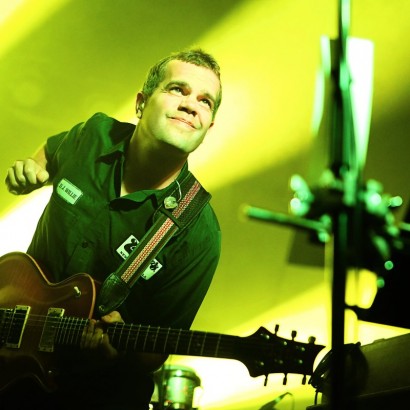 Electric Guitarist Brendan Bayliss holds a rock pose while performing under concert lights